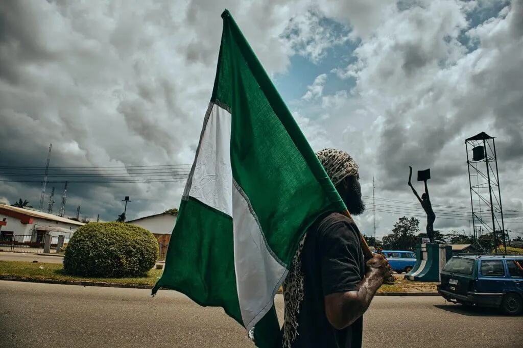 Nigerian States and Capitals with Slogans and Resources 8 man holding a flag of nigeria