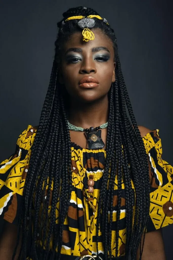 attractive woman with african pigtails hairstyle in yellow dress with exotic pattern