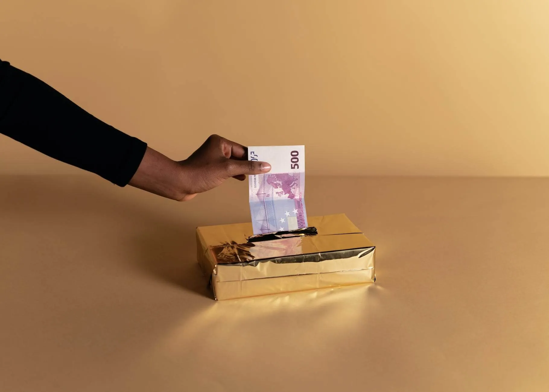 person putting money inside the gold box